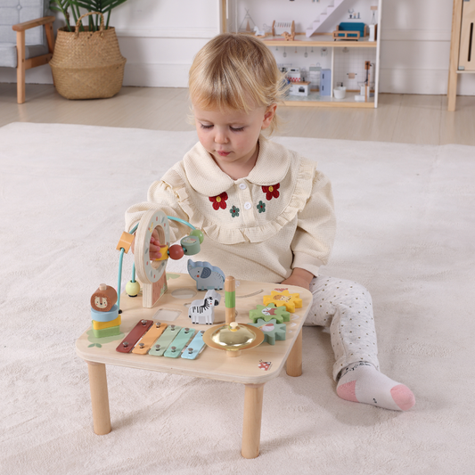 bebe juega con mesa musical de actividades de madera