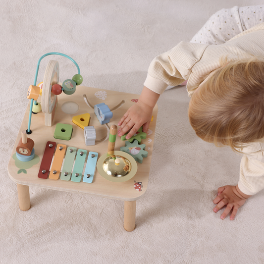 bebe juega con mesa musical de actividades de madera
