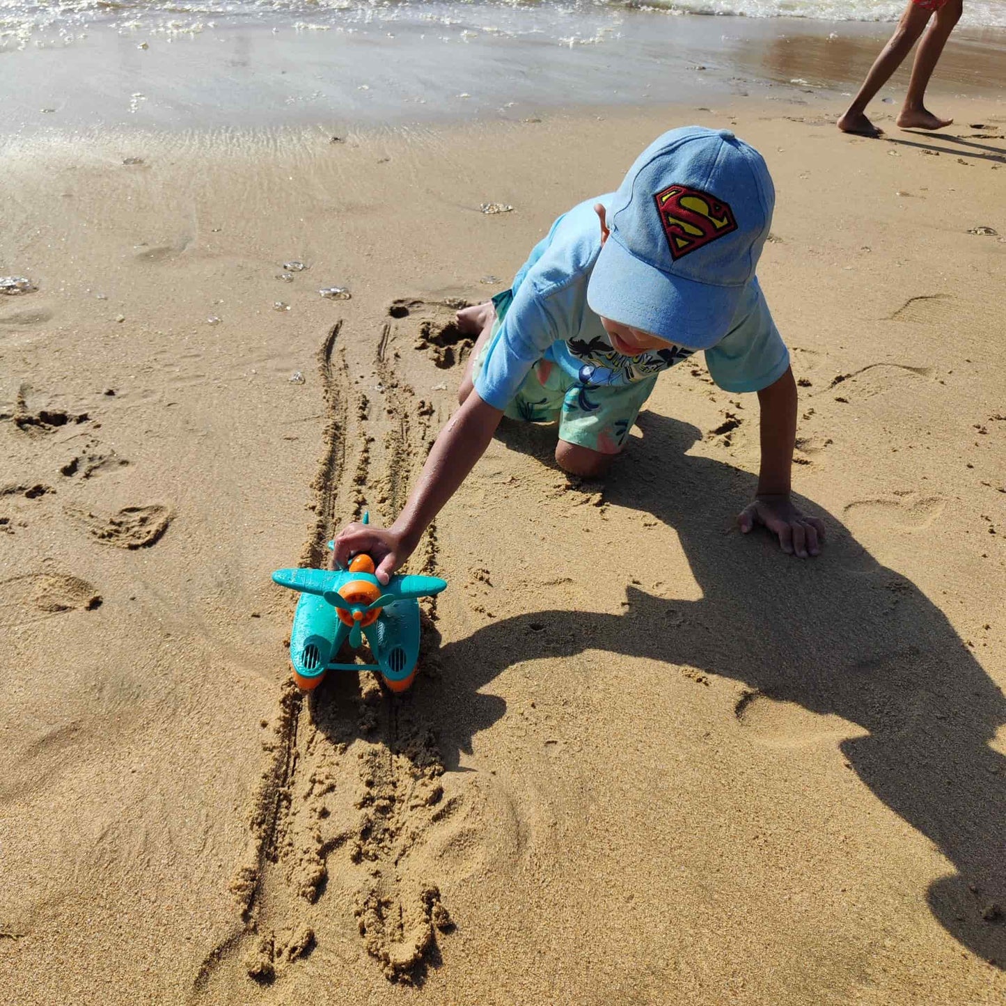 Niño jugando con hidroavión eco-friendly en la playa, fomentando la imaginación y coordinación