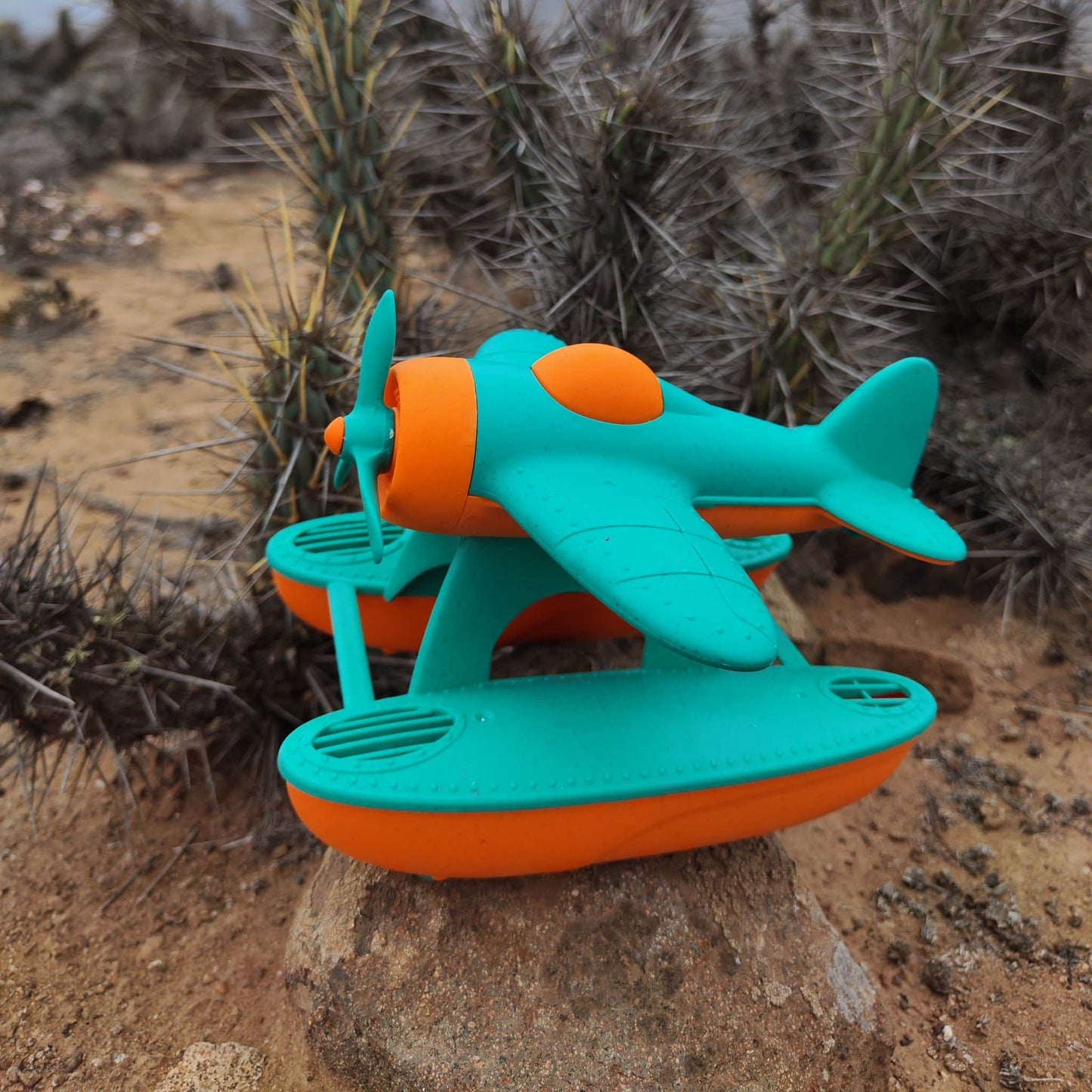 Hidroavión eco-friendly de paja de trigo que flota, color anaranjado y calipso, en un escenario desértico