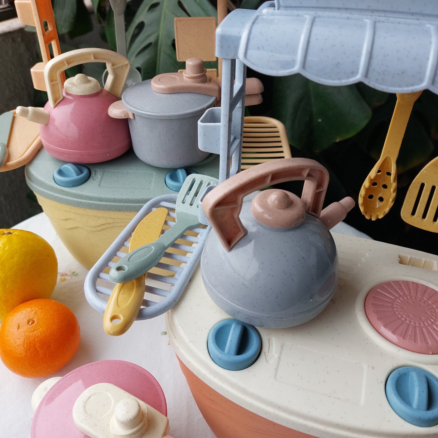 Set de cocina portátil de bioplástico de paja de trigo en dos colores (coral clar y amarillo), incluye hornilla, utensilios tetera y olla a presión. La hornilla funciona como caja de almacenamiento del juguete