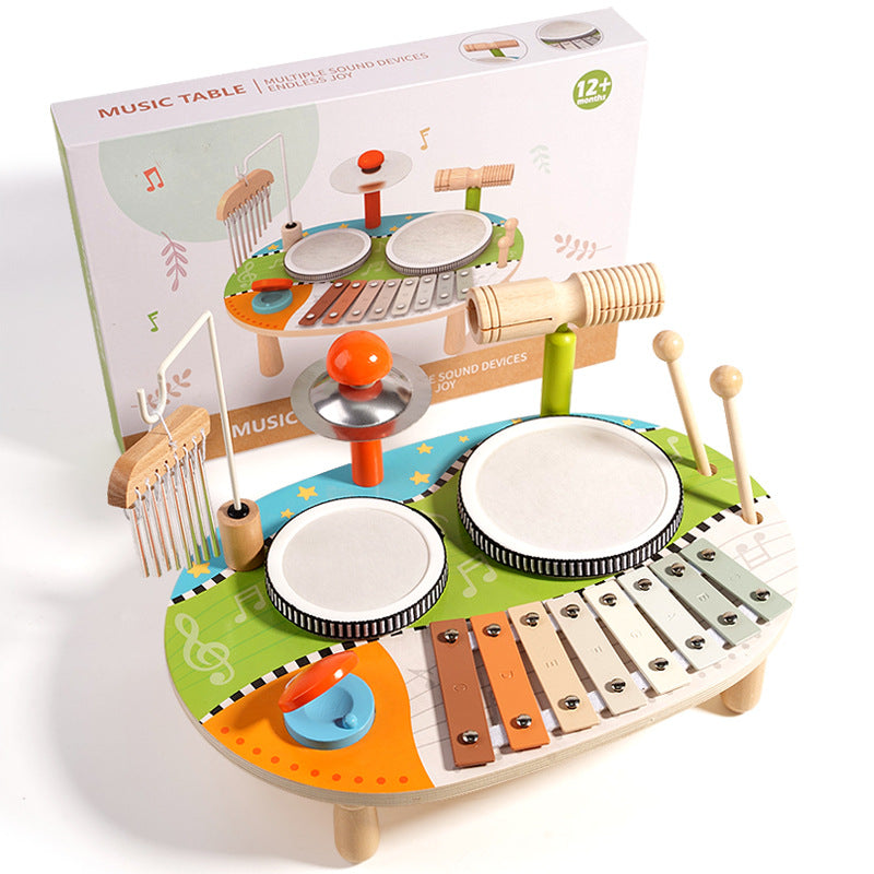 Set de percusión infantil 5‑en‑1 con instrumentos de madera eco‑friendly, 2 tambores, metalófono de 8 notas, platillo, güiro, carillón y 2 baquetas, con su empaque de fondo