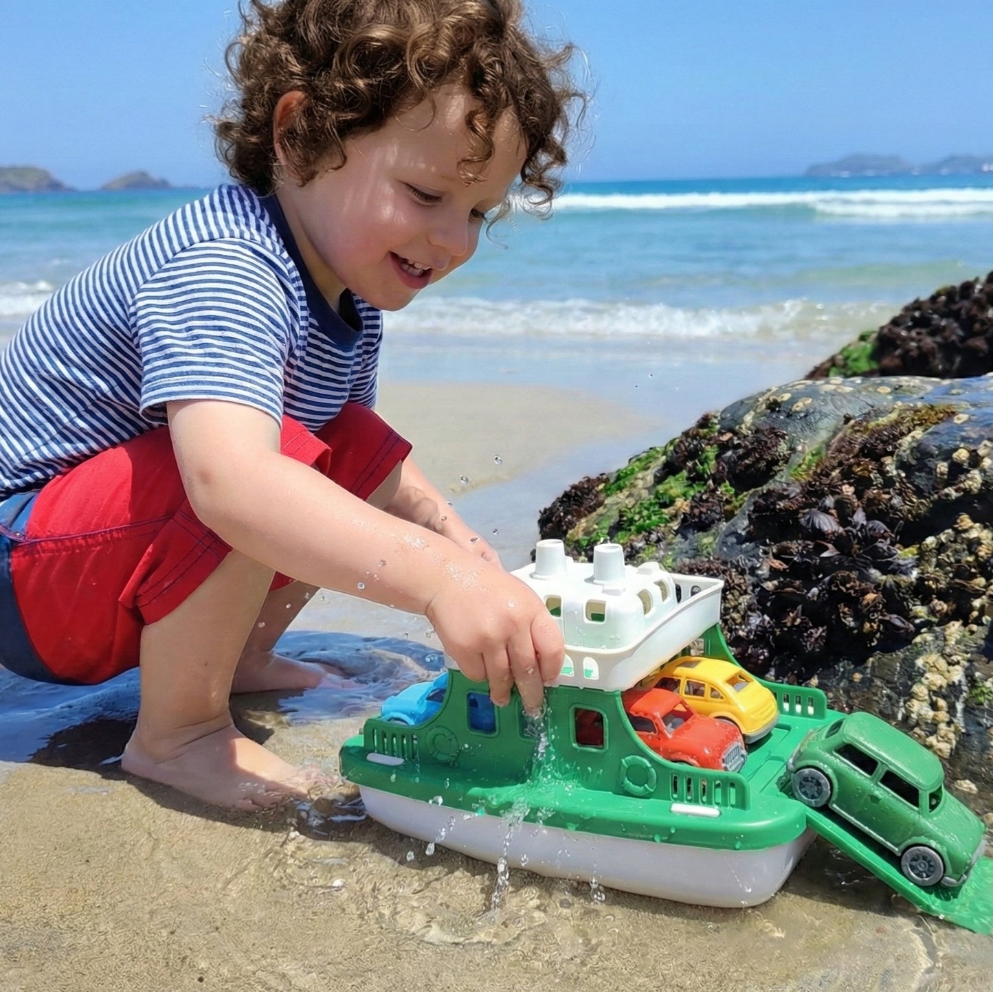 Niño jugando en la playa con el Ferry de plástico reciclable y 4 autitos