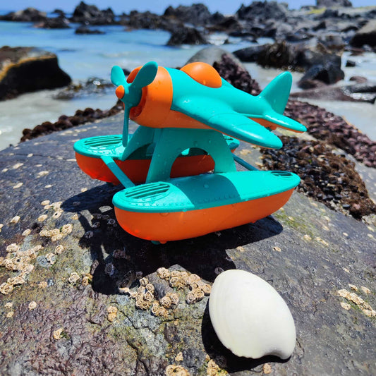 Hidroavión eco-friendly de paja de trigo que flota, color anaranjado y calipso, en un escenario natural de playa