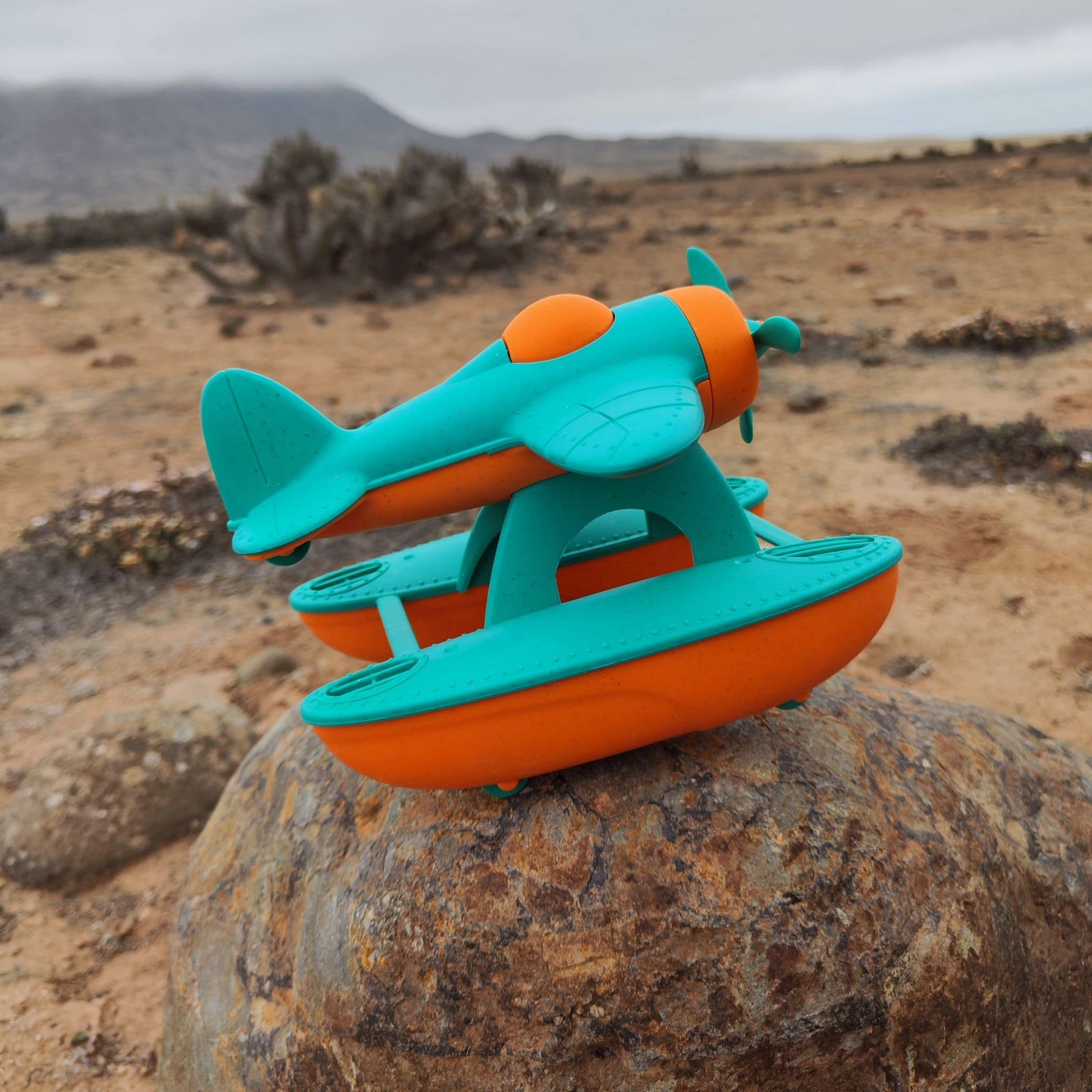 Hidroavión eco-friendly de paja de trigo que flota, color anaranjado y calipso, en un escenario desértico