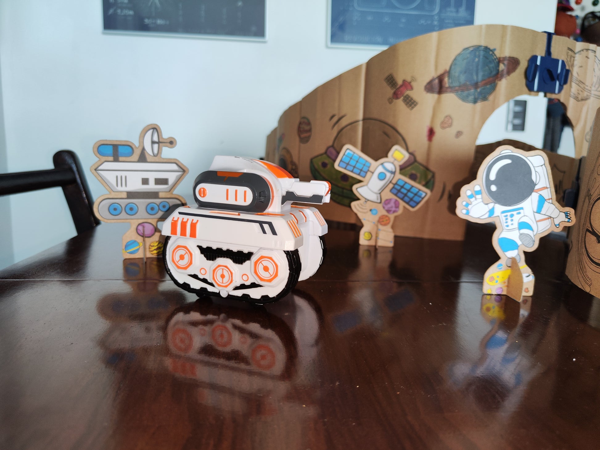 Detalle de los accesorios de la pista espacial modular en cartón: el vehículo y las figuras de nave espacial, satélite y astronauta