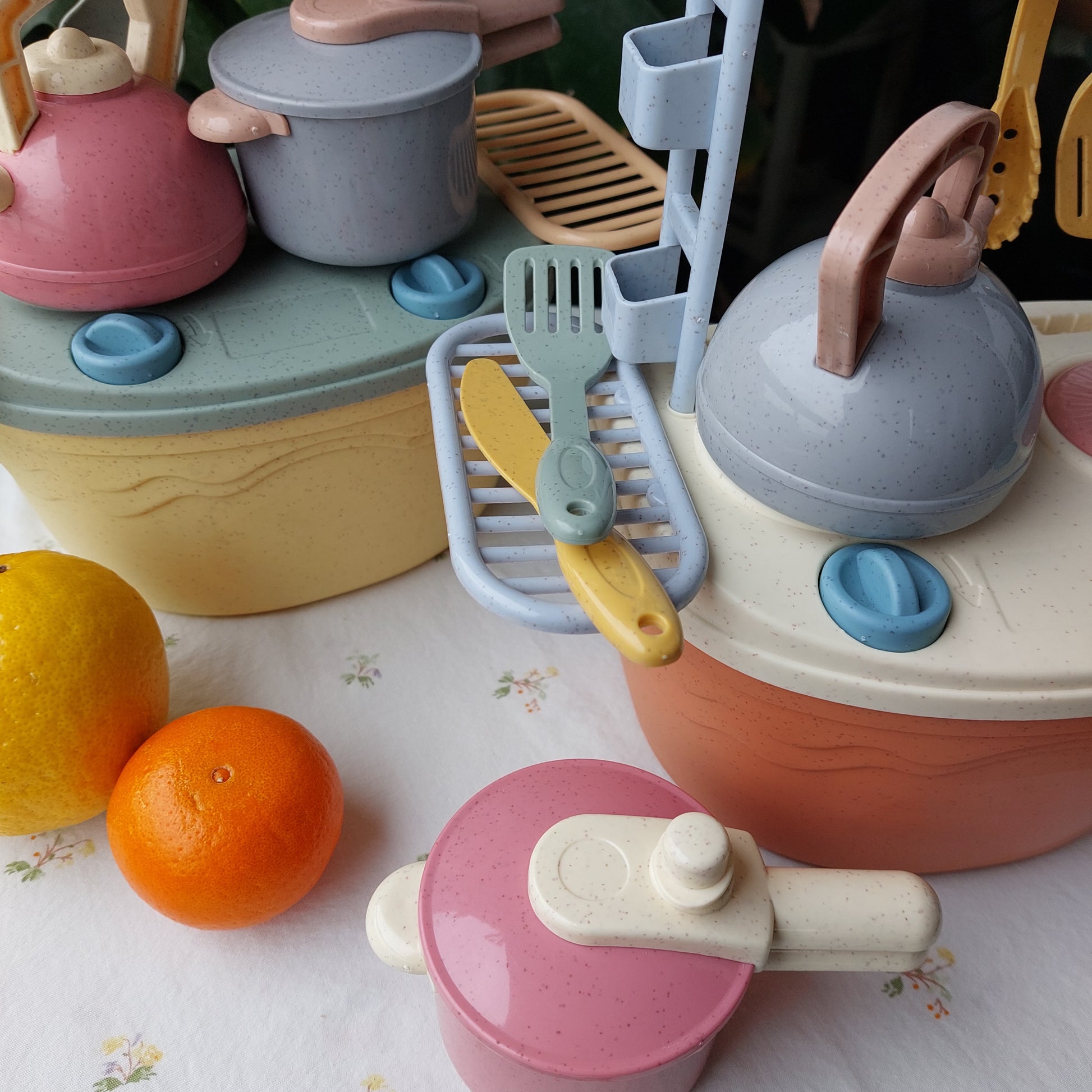 Set de cocina portátil de bioplástico de paja de trigo, en dos colores (coral claro y amarillo). Incluye hornilla, utensilios tetera y olla a presión. La hornilla funciona como caja de almacenamiento del juguete